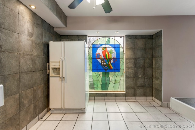 tiled entryway with ceiling fan and tile walls