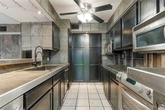 kitchen with tile countertops, sink, ceiling fan, light tile patterned floors, and appliances with stainless steel finishes