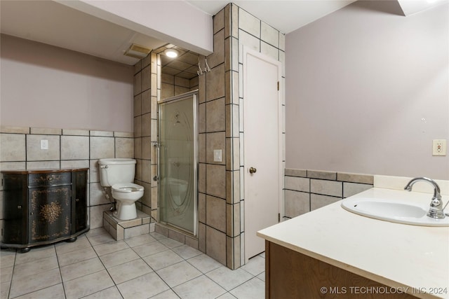 bathroom with toilet, vanity, tile patterned floors, and tile walls