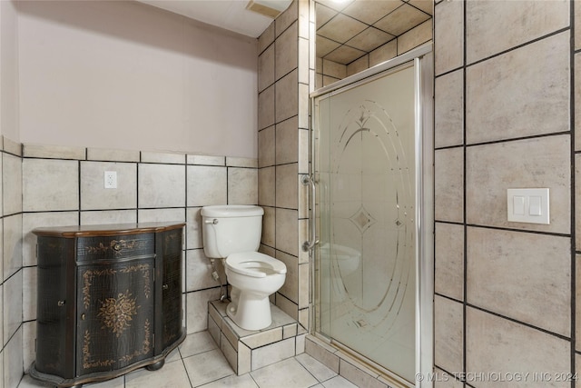 bathroom featuring tile patterned flooring, toilet, and tile walls