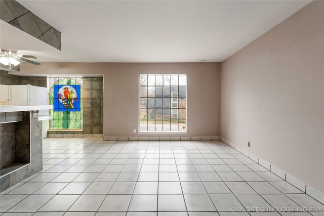 unfurnished living room featuring ceiling fan, light tile patterned floors, and a fireplace