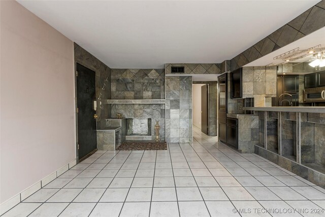 unfurnished living room featuring a fireplace, light tile patterned floors, and tile walls