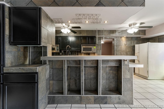 kitchen with white refrigerator, light tile patterned floors, and tile walls