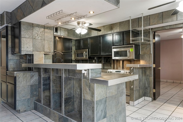 kitchen with range with electric cooktop, ceiling fan, light tile patterned floors, a kitchen bar, and kitchen peninsula