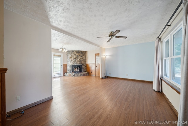 unfurnished living room with hardwood / wood-style flooring, ceiling fan with notable chandelier, a fireplace, and a textured ceiling