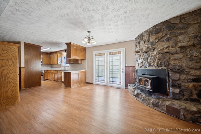 kitchen featuring a wood stove, hanging light fixtures, a textured ceiling, and light hardwood / wood-style floors