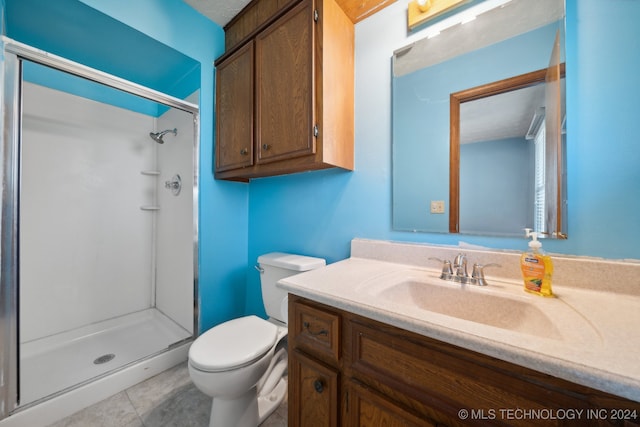 bathroom with tile patterned floors, vanity, toilet, and a shower with shower door