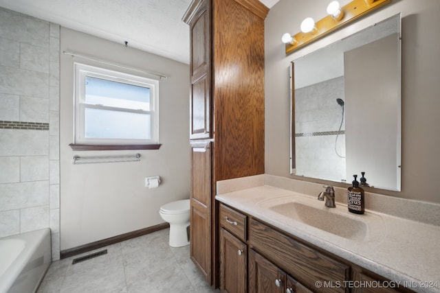 full bathroom with vanity, tile patterned floors, tiled shower / bath combo, toilet, and a textured ceiling