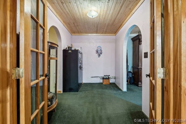 hallway featuring dark colored carpet, wood ceiling, and ornamental molding