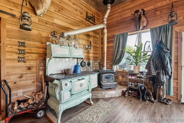 miscellaneous room featuring hardwood / wood-style flooring, a wood stove, and wood walls