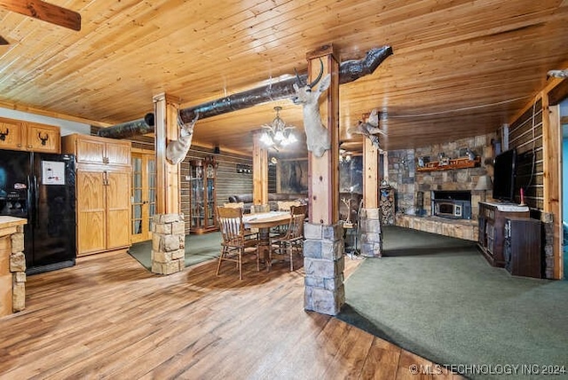 kitchen with black refrigerator, wood ceiling, decorative light fixtures, a fireplace, and hardwood / wood-style floors