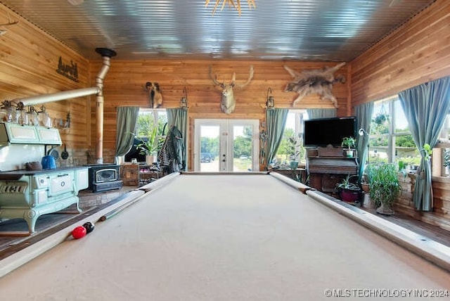 miscellaneous room with pool table, a wood stove, wooden walls, and french doors