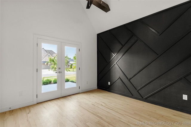 empty room with french doors, vaulted ceiling, and light hardwood / wood-style flooring