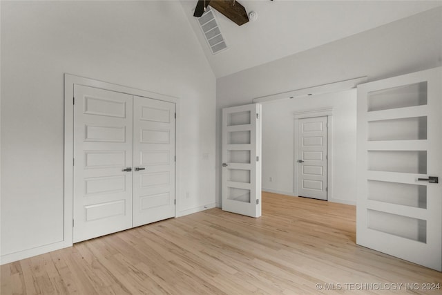 unfurnished bedroom featuring a closet, high vaulted ceiling, light hardwood / wood-style flooring, and ceiling fan