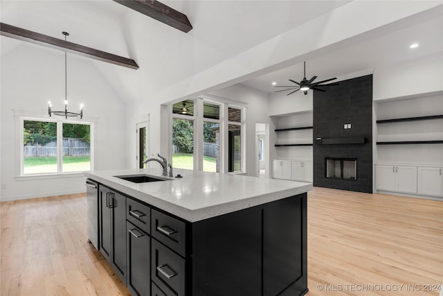 kitchen featuring sink, beamed ceiling, light hardwood / wood-style floors, decorative light fixtures, and a fireplace