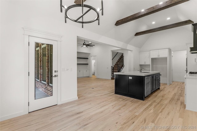 kitchen featuring ceiling fan with notable chandelier, beam ceiling, a center island with sink, white cabinets, and light hardwood / wood-style floors