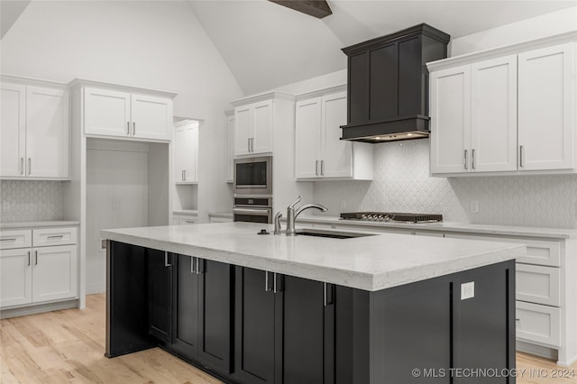 kitchen featuring sink, light hardwood / wood-style flooring, a center island with sink, white cabinets, and appliances with stainless steel finishes