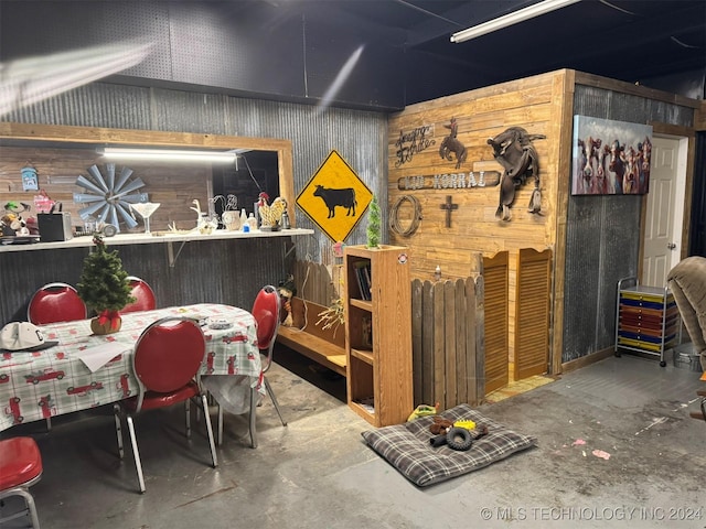 playroom featuring wooden walls and concrete floors