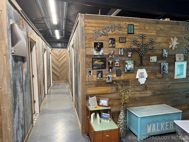 corridor with concrete flooring and wooden walls