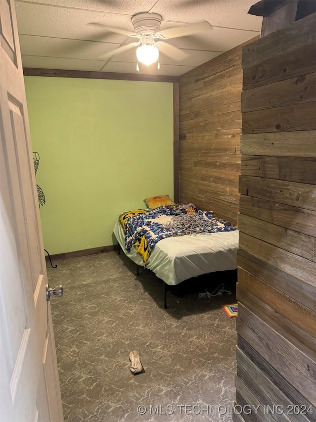 bedroom featuring ceiling fan and wooden walls