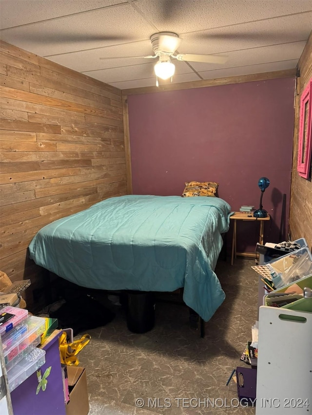 bedroom featuring ceiling fan and wooden walls