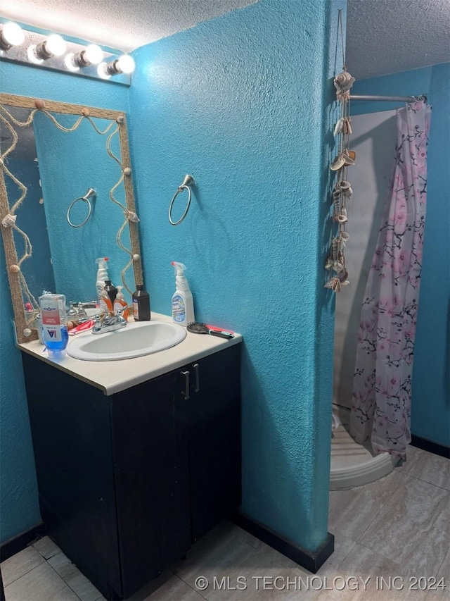 bathroom with tile patterned floors, a shower with curtain, a textured ceiling, and vanity