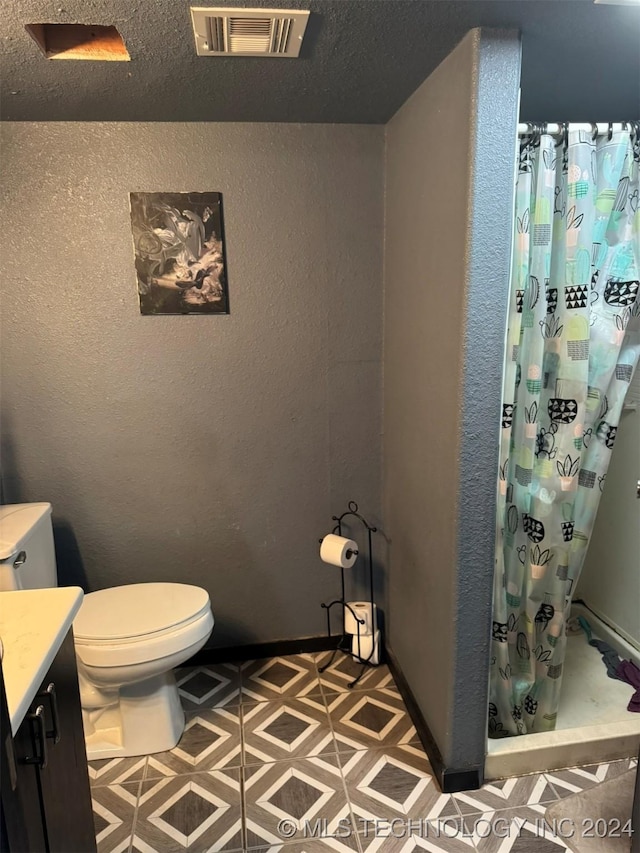 bathroom with toilet, vanity, and walk in shower