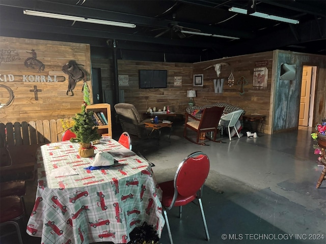 dining area featuring ceiling fan, concrete flooring, and wooden walls