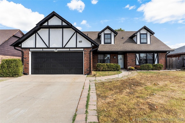 english style home featuring a garage and a front lawn