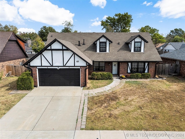 english style home with a garage and a front lawn