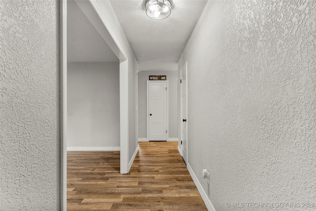 hallway with hardwood / wood-style floors and a textured ceiling