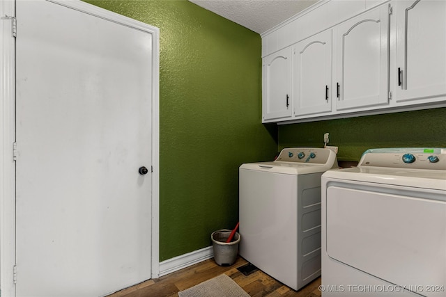 washroom featuring washer and clothes dryer, cabinets, a textured ceiling, and dark wood-type flooring