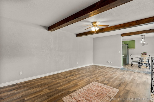 unfurnished room featuring ceiling fan, beamed ceiling, wood-type flooring, and a textured ceiling