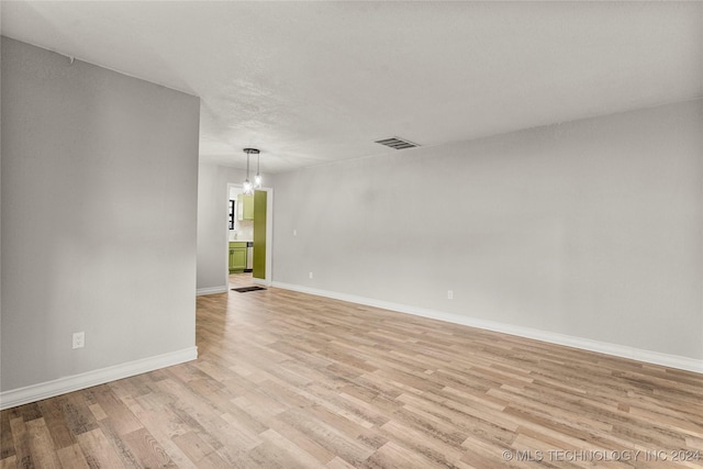 empty room featuring an inviting chandelier and light hardwood / wood-style flooring