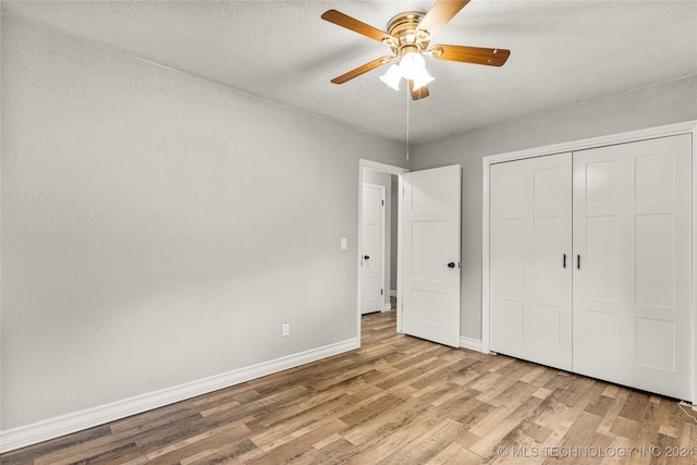 unfurnished bedroom featuring a textured ceiling, light wood-type flooring, a closet, and ceiling fan