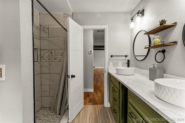 bathroom with a tile shower, vanity, wood-type flooring, and a textured ceiling