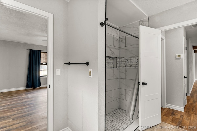 bathroom featuring tiled shower, a textured ceiling, and hardwood / wood-style flooring