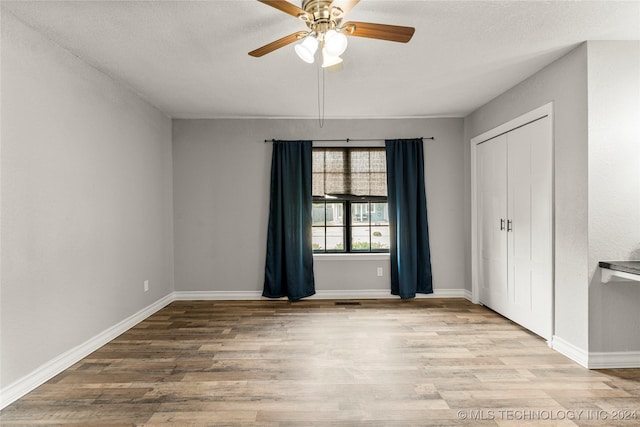 unfurnished bedroom with a textured ceiling, a closet, light hardwood / wood-style flooring, and ceiling fan