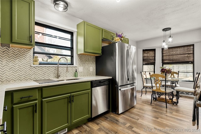 kitchen with hardwood / wood-style floors, a healthy amount of sunlight, green cabinets, and appliances with stainless steel finishes