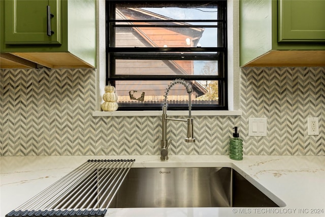 kitchen featuring decorative backsplash, light stone counters, sink, and green cabinetry