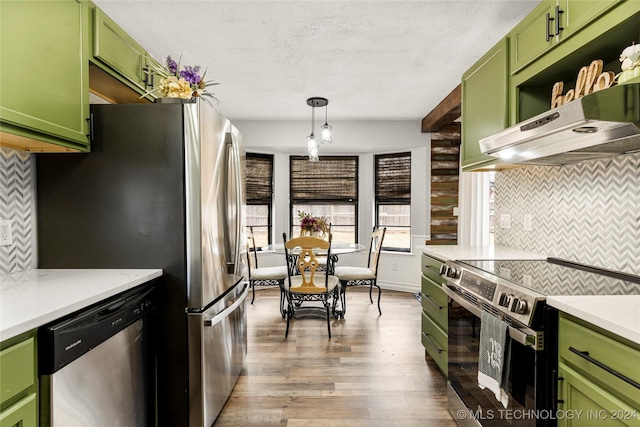 kitchen with appliances with stainless steel finishes, ventilation hood, dark wood-type flooring, pendant lighting, and green cabinets