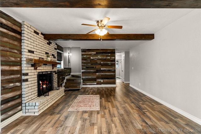 living room featuring ceiling fan, dark hardwood / wood-style flooring, beamed ceiling, and a brick fireplace