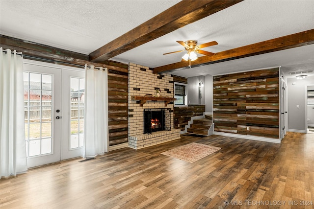 unfurnished living room with french doors, ceiling fan, a fireplace, a textured ceiling, and wood-type flooring