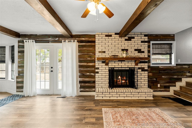 unfurnished living room featuring hardwood / wood-style flooring, ceiling fan, beam ceiling, and a textured ceiling