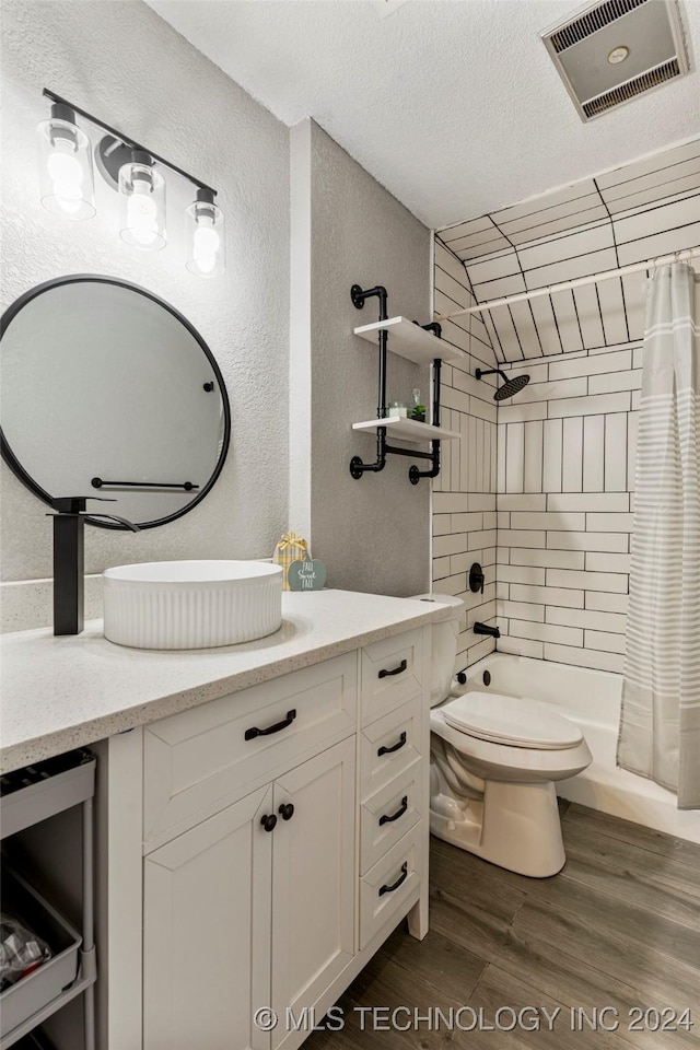 full bathroom featuring wood-type flooring, a textured ceiling, toilet, shower / tub combo with curtain, and vanity