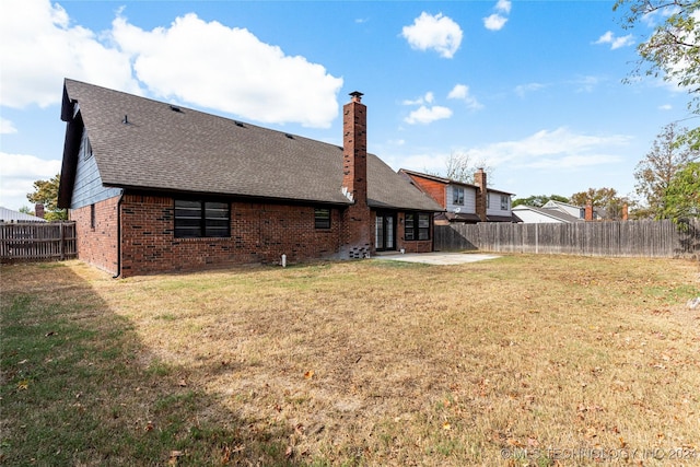 back of house with a lawn and a patio