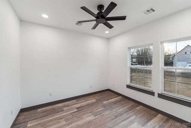 empty room with baseboards, visible vents, wood finished floors, and recessed lighting