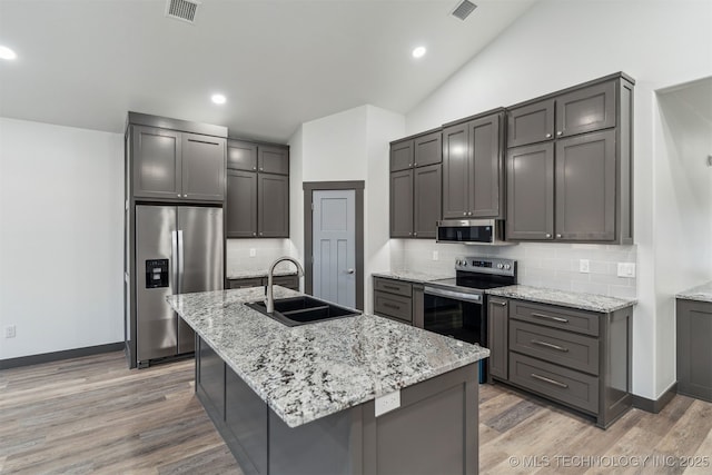 kitchen with appliances with stainless steel finishes, lofted ceiling, visible vents, and a sink