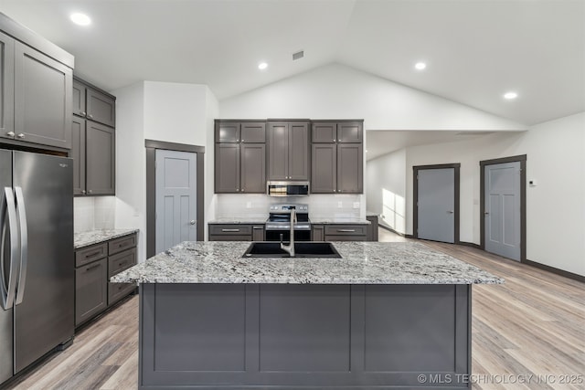 kitchen featuring stainless steel appliances, lofted ceiling, visible vents, light wood-style flooring, and a sink