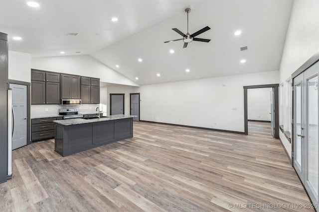 kitchen featuring stainless steel appliances, open floor plan, a sink, and high vaulted ceiling